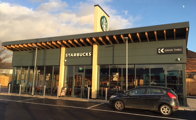 straight view of a spacious Starbucks cafe with a drive thru at sunset