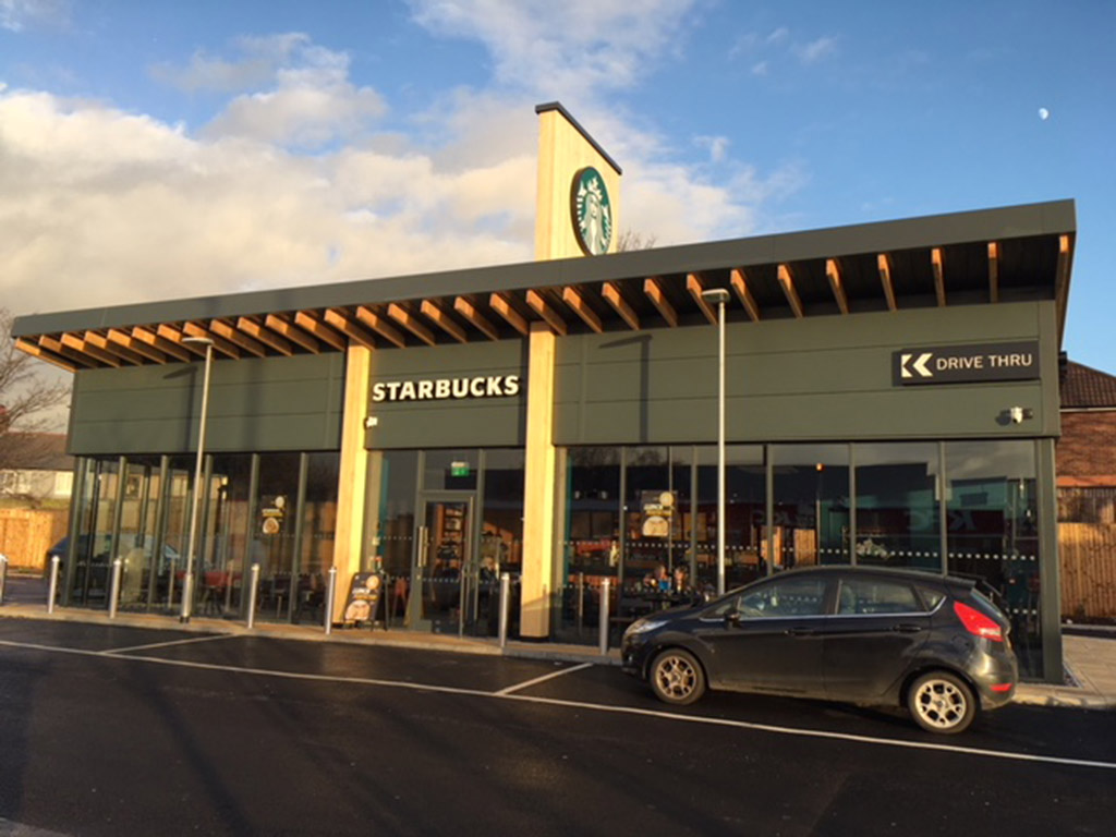 straight view of a spacious Starbucks cafe with a drive thru at sunset